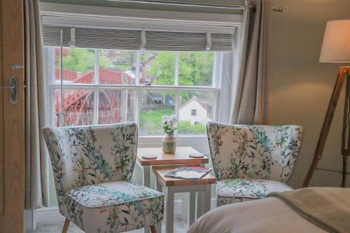 艾恩布里奇Bridgeside Rooms的一间卧室配有两把椅子、一张桌子和一个窗户。