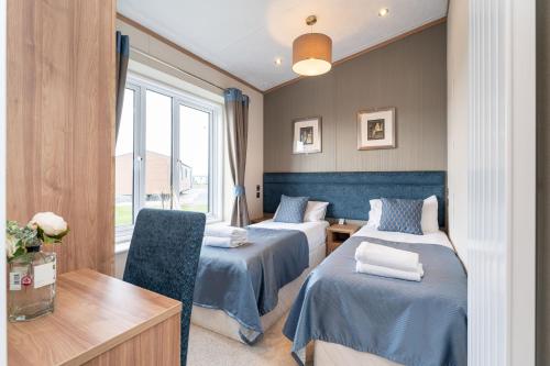 圣安德鲁斯Stewarts Resort Lodge 18的客房设有两张床、一张桌子和一个窗户。