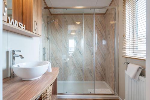圣安德鲁斯Stewarts Resort Lodge 18的一间带水槽和玻璃淋浴的浴室