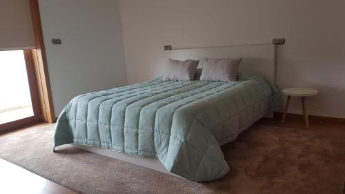 维拉诺瓦-德法马利Oktavihu House的一间卧室配有一张带绿色棉被的床和一张桌子