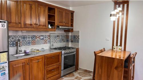 奥塔瓦洛Kimsa Wasi III的厨房配有木制橱柜和炉灶烤箱。
