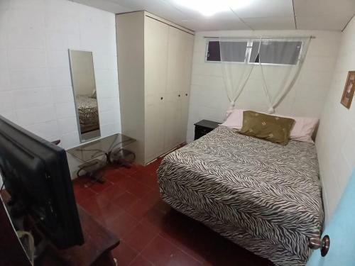 Nueva San SalvadorSanta Tecla Acogedora Guest House的一间小卧室,配有一张床和电视