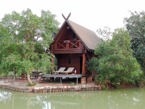 Tây NinhLA'S FARMSTAY的水边的小木屋,配有野餐桌