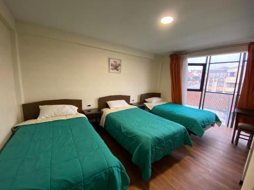 苏克雷Copacabana Hostal的客房设有两张带绿床单的床和窗户。