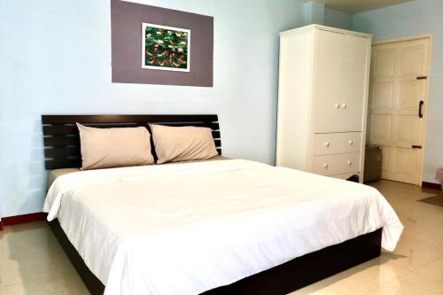Tha Boโรงแรมเจเอสเพลส的卧室配有白色大床和梳妆台