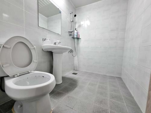 Wando莞岛尼西亚宾馆的白色的浴室设有卫生间和水槽。