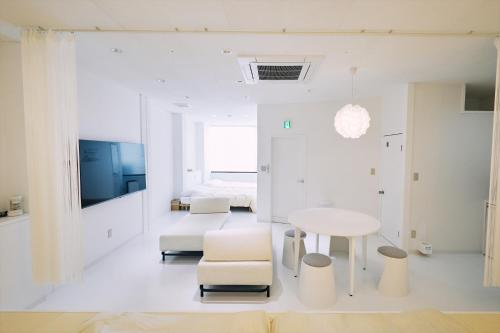 高知「まちのアトリエ」STAY UWU 004的白色的客房配有桌子和床。