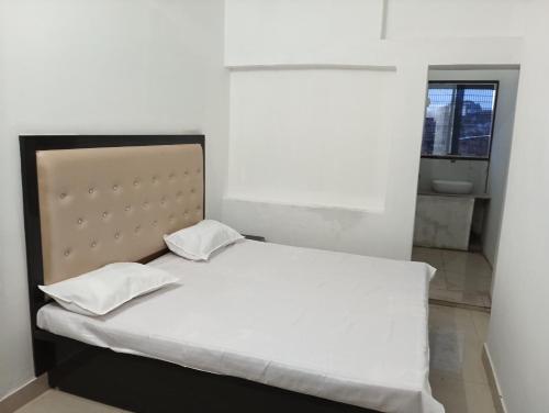 FaizābādMAHENDRA HOME STAY的卧室内的一张带两个枕头的白色床