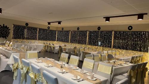 格伦因尼斯Club Hotel的一个带白色桌椅的大型宴会厅