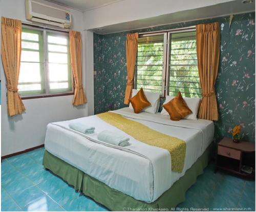 Ban Rai淮黎康乡村之家酒店的一间卧室设有一张大床和两个窗户。