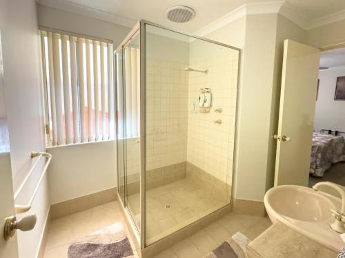 珀斯阿斯科特天鹅住宿加早餐旅馆的一间带玻璃淋浴和水槽的浴室