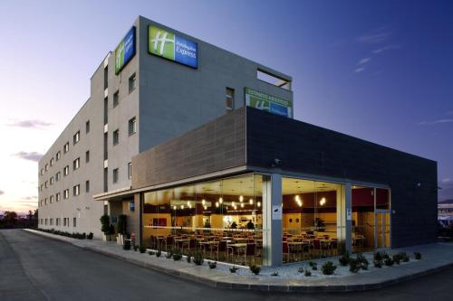 马拉加Holiday Inn Express Málaga Airport, an IHG Hotel的一座大建筑,里面设有桌椅