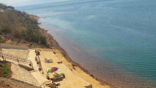 索瓦马Comfy Stays Sea View Apartments at DeadSea Samarah Resort- FAMILIES & COUPLES DURING WEEKENDS & PUBLIC HOLIDAYS的沙滩上沙滩上摆放着椅子和遮阳伞