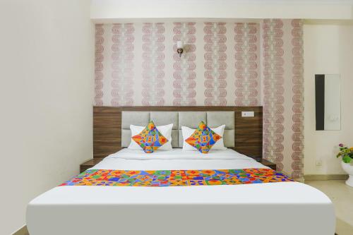 诺伊达FabHotel Corporate Stay的卧室配有一张带彩色枕头的大型白色床。