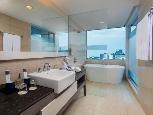 马卡萨ASTON Makassar Hotel & Convention Center的带浴缸、水槽和浴缸的浴室