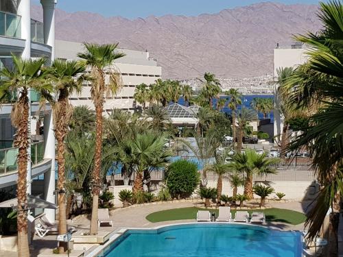 埃拉特Palmore Top Luxury Resort First line of the Seaside的享有带游泳池和棕榈树的度假村的景致