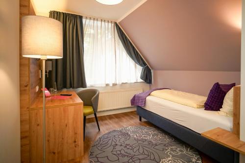 比勒费尔德Hotel Lindenhof的一间卧室配有一张床、一张书桌和一个窗户。