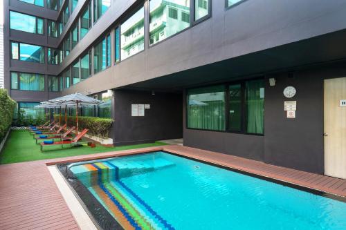 曼谷VIC 3 Bangkok Hotel的大楼前的游泳池