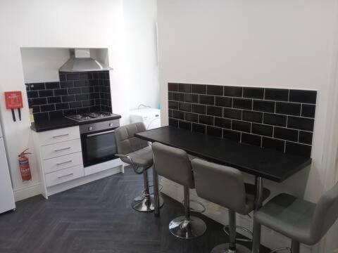 伯恩利Double-bed (E1) close to Burnley city centre的厨房配有黑色的桌子和一些椅子
