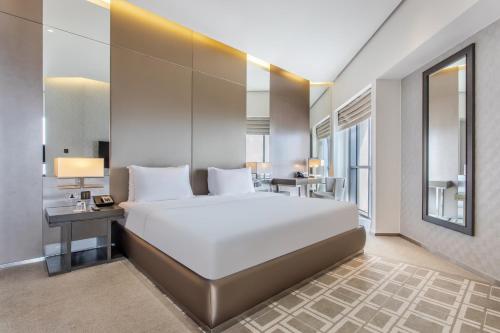 迪拜Spacious Studio Apartment in Hyatt Regency Dubai Creek Heights by the S Holiday Homes的卧室配有一张白色大床和一张书桌