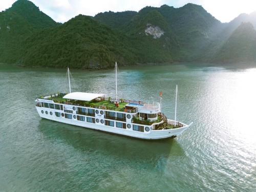 下龙湾Le Journey Calypso Pool Cruise Ha Long Bay的船上的船,背靠群山