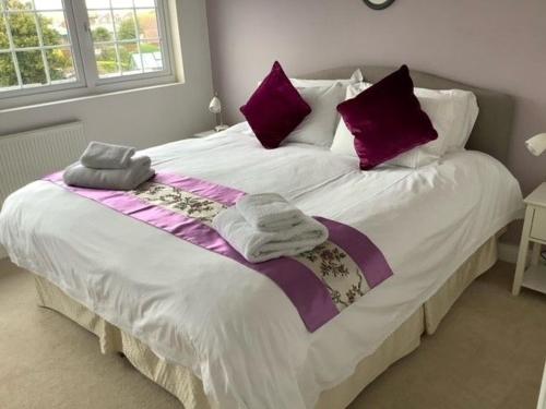 塞尔西Caedwalla House, Selsey的一间卧室配有一张大床,提供紫色和白色枕头
