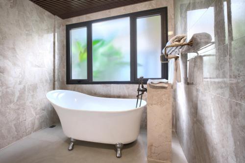 岘港THE BLOSSOM RESORT ISLAND - All Inclusive的带浴缸的浴室和窗户