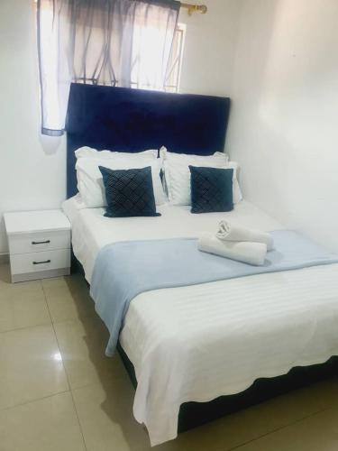 KitweBlueView Apartments的客房内的两张床,配有白色床单和蓝色床头板