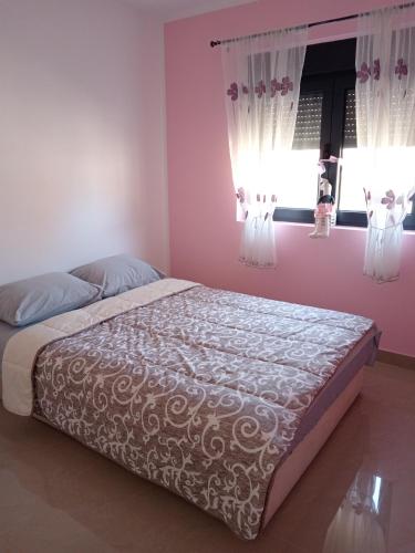 弗尔沙茨Apartman SARA的卧室内的一张床位,卧室设有粉红色的墙壁和窗户
