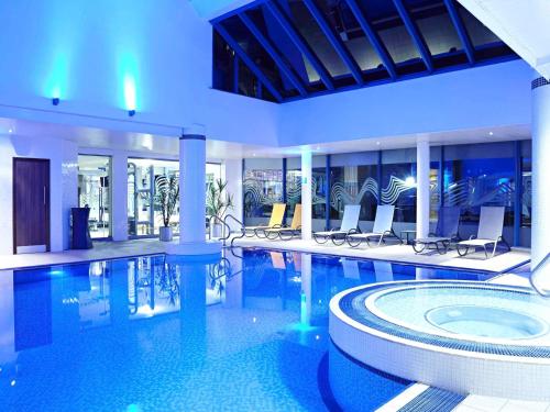 卡迪夫诺富特加的夫中心酒店的大楼内带椅子的大型游泳池