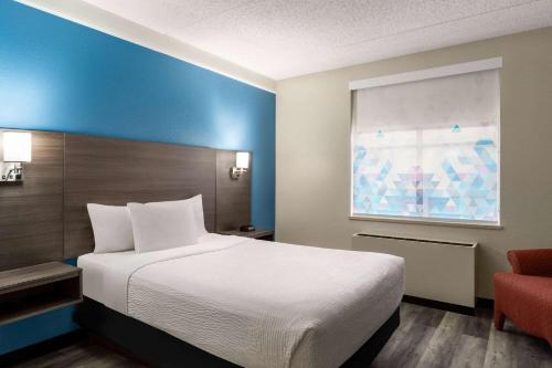 麦迪逊麦迪逊美国中心拉金塔旅馆及套房的一间卧室配有一张大床和一张红色椅子