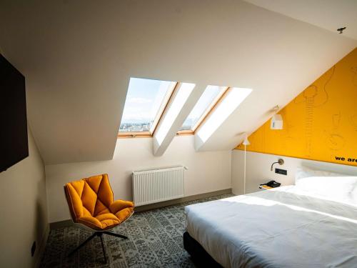 锡比乌Ibis Styles Sibiu Arsenal的一间卧室设有一张床、一个窗口和一把椅子