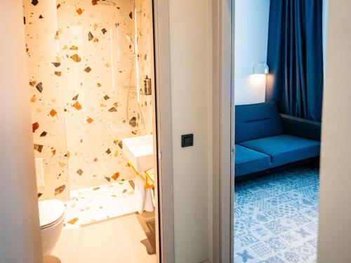 锡比乌Ibis Styles Sibiu Arsenal的浴室设有蓝色沙发,毗邻卫生间