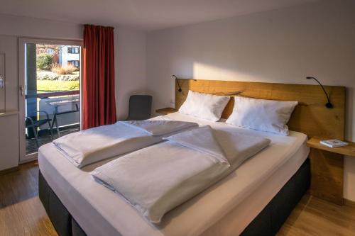 奥伊-米特尔贝格Appartement-Hotel-Allgayer的一间卧室配有一张带白色床单的大床