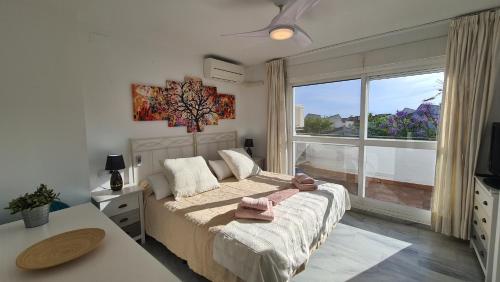 马贝拉Lunamar El mejor Resort en la mejor Playa的一间卧室设有一张床和一个大窗户
