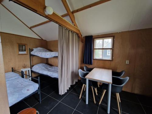 De ValomBlokhut camping De Zilveren Maan的客房设有两张双层床和一张桌子及椅子。