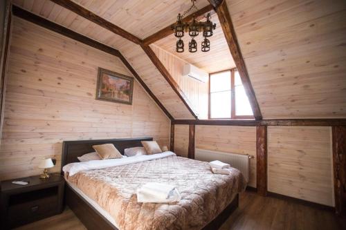 BrzezhanyГотель Бережани的一间带一张大床的卧室,位于带木墙的房间