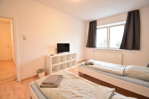 波鸿CoreRooms - Apartment Bochum Wattenscheid的一间卧室设有两张床、一台电视和一扇窗户。