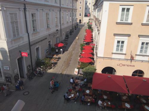 萨尔茨堡arte vida boutique guesthouse的街道上方的桌子和红色遮阳伞