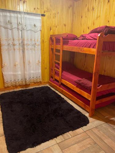 美洲花园Cabañas “La India”的一间卧室配有两张双层床和黑色地毯。