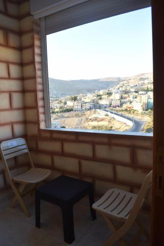 瓦迪穆萨Petra rose city的客房设有带2把椅子和1张桌子的窗户。