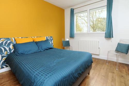 沙特尔Le Saint-Brice的一间卧室配有一张带蓝色棉被的床和窗户。