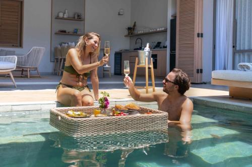 坎古Sin Nombre Bali - Sauna, Ice Bath & Roof Terrace的男男女女在游泳池里拿着酒杯