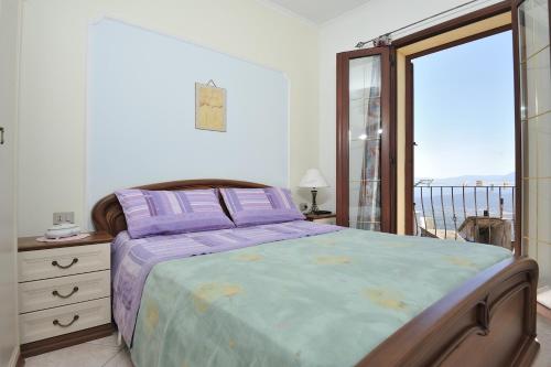 包内伊Apartments Baunei的一间卧室配有一张紫色床单和一个阳台。