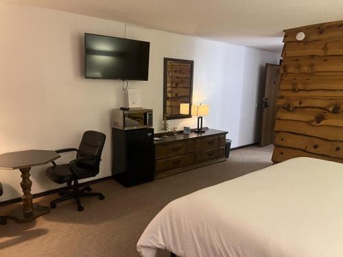 TomahawkBridge Inn Tomahahwk - Room 106 ,1 King Size Bed,1 Recliner, Walkout, River View的一间卧室配有一张床、一张书桌和一台电视