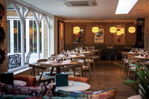 泰晤士河畔里士满Harbour Hotel & Spa Richmond的用餐室设有桌椅和窗户。