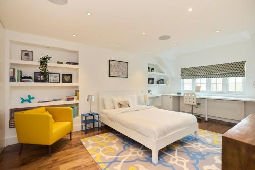 伦敦The Clapham Crib - Spacious 4BDR House with Patio的一间卧室配有一张床和一张黄色椅子