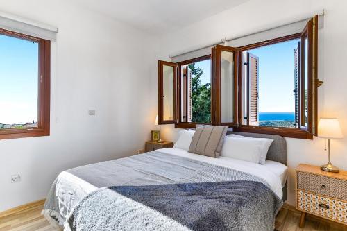 库克里亚1 bedroom Apartment Pyrgos with beautiful sea and sunset views, Aphrodite Hills Resort的一间卧室设有一张床和两个窗户。
