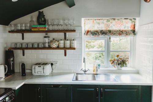 图克斯伯里Two Luxury Cosy Cottages的厨房配有绿色橱柜、水槽和窗户