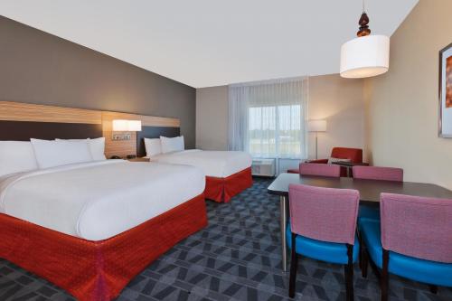 大急流城TownePlace Suites by Marriott Grand Rapids Airport Southeast的酒店客房带两张床和一张桌子以及椅子。